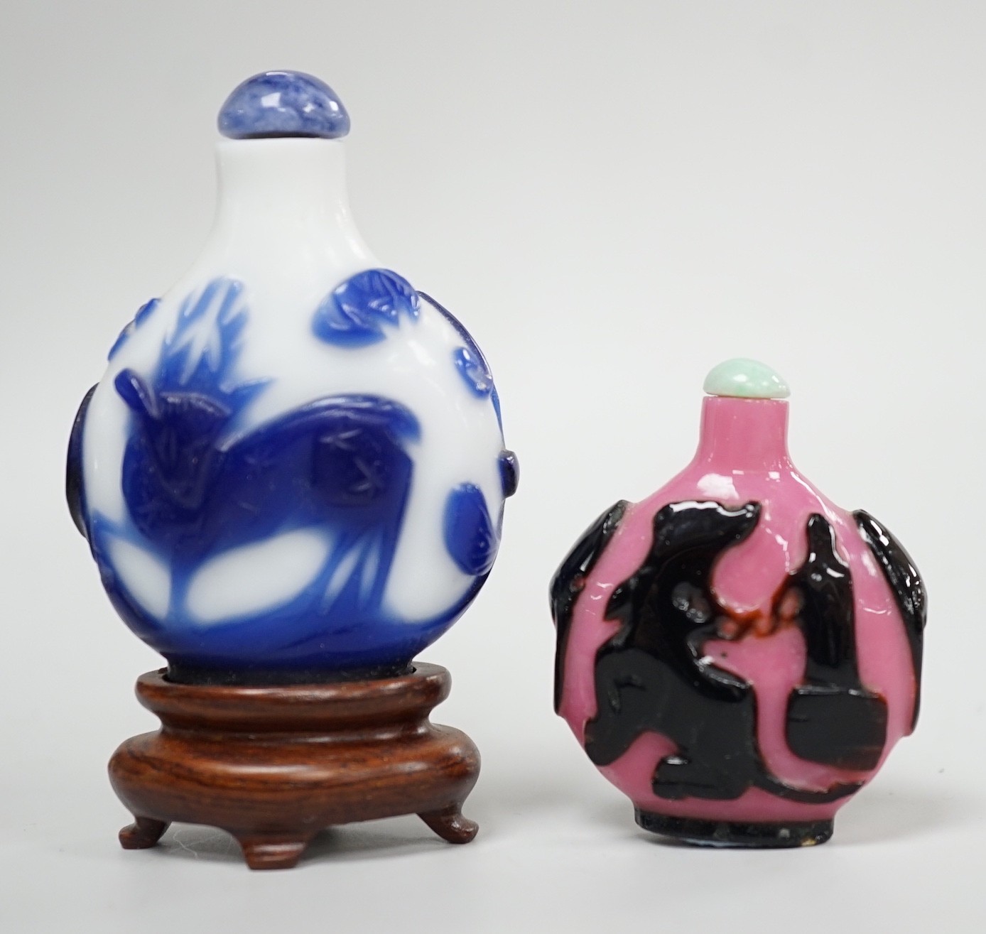 Two Chinese overlay glass snuff bottles, the black and pink bottle in imitation of shadow agate, 18th century, decorated with an eagle and the moon the reverse with a dog tied to a chain, 4.3cm, the blue and white exampl